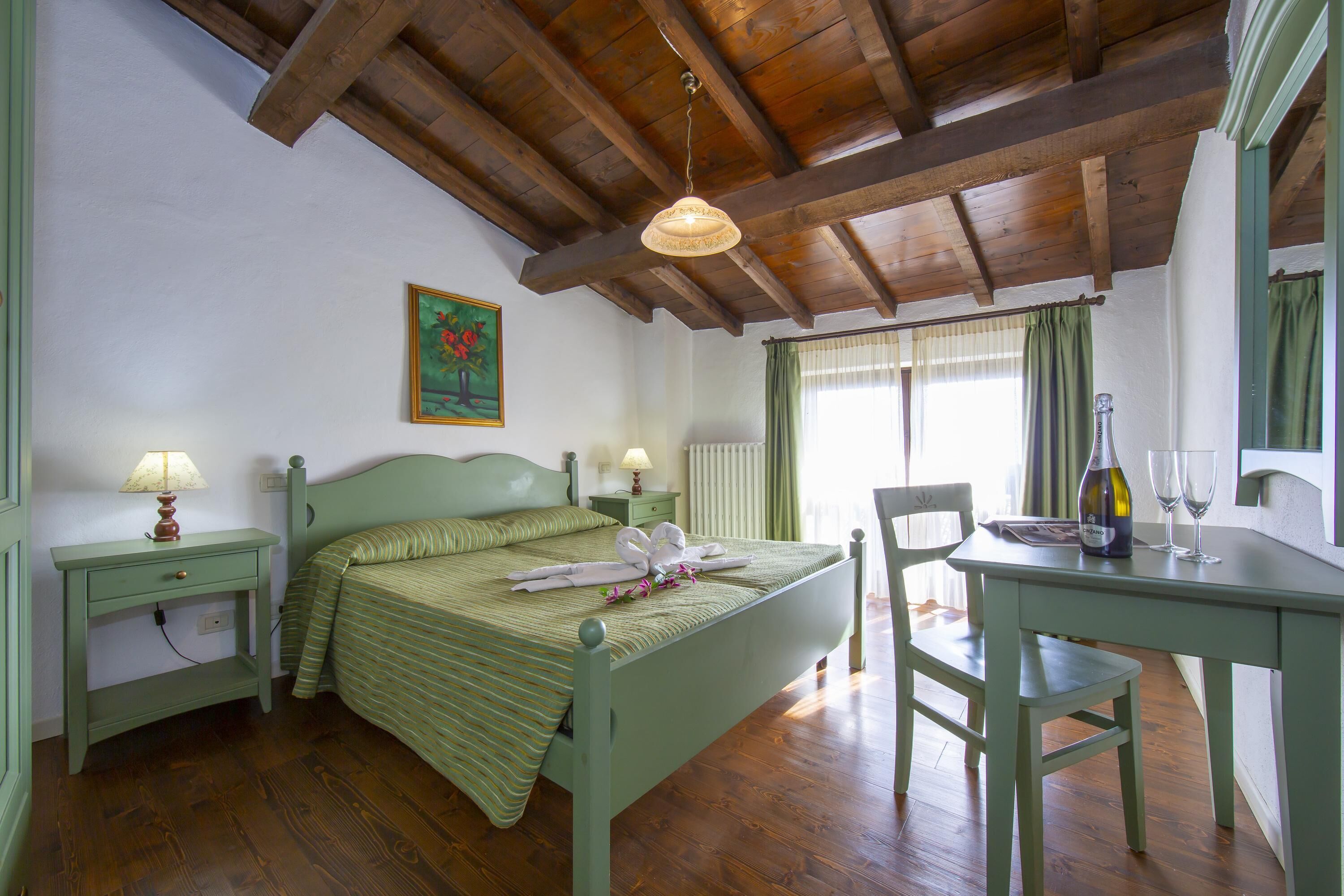 A room with a bed, bedside tables, a desk, and a chair.