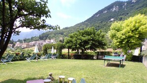 A grassy outdoor area with lounge chairs, a ping pong table, and a small red table. - Violetta in Hilly Area (Gargnano)