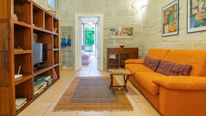 A living room with a wooden bookshelf, a television, a sofa, and a chess table. - Myhome In The Centre Of Lecce (Lecce)