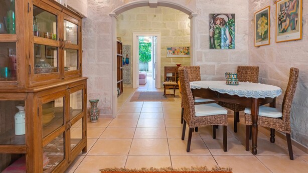 A dining area with a round table, wicker chairs, and a cabinet with glass doors. - Myhome In The Centre Of Lecce (Lecce)