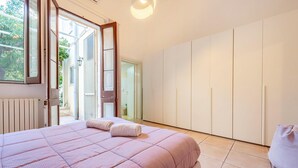 A bedroom with a large bed, a wardrobe, and a door leading to a balcony. - Myhome In The Centre Of Lecce (Lecce)
