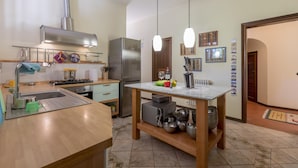 Une cuisine moderne dotée d’appareils électroménagers en acier inoxydable, d’un plan de travail en bois et de luminaires suspendus.