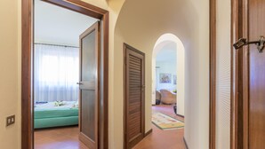 Un couloir avec un lit, une porte fermée et un tapis qui mène à un espace de vie.