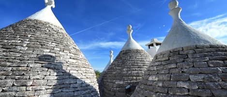 A row of traditional stone-roofed buildings with conical tops and white decorative elements.