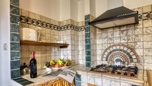 A kitchen with a gas stove, a wine bottle, and a fruit bowl on the counter. - Tenuta Di Litiano With Pool (Roccastrada)