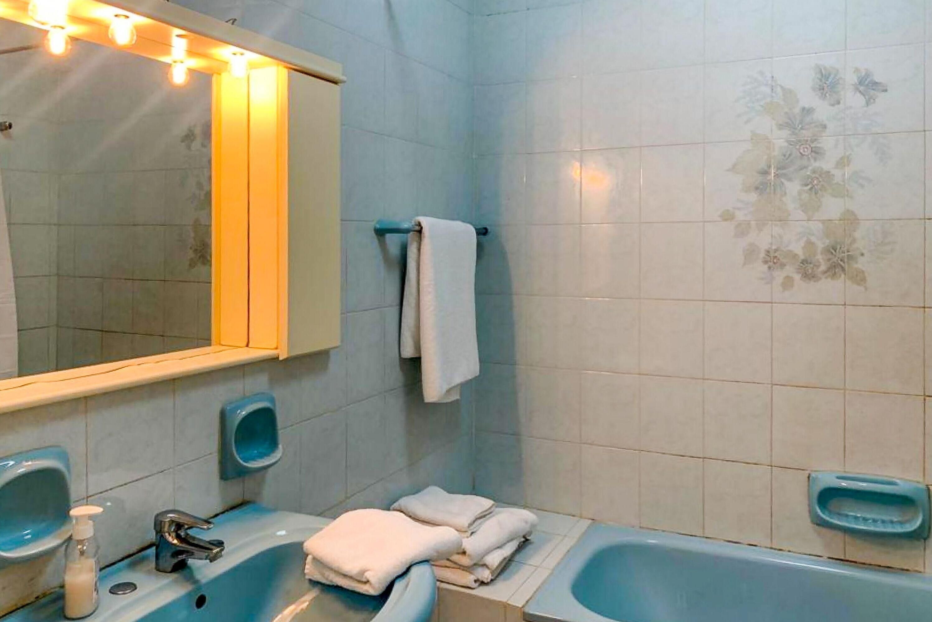 A bathroom with two sinks, a bathtub, and a mirror. There are towels and soap dispensers.
