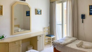 Ένα δωμάτιο ξενοδοχείου με δύο κρεβάτια, έναν μεγάλο καθρέφτη, ένα γραφείο, μια καρέκλα και ένα τηλέφωνο στον τοίχο.