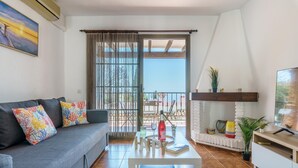 A living room with a grey sofa, colorful cushions, a coffee table, and a TV on a wooden stand. - Sunny Tranquility With Pool (Benalmádena)