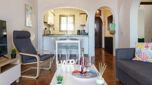 A modern living room with a dining area, a kitchen visible through an archway, and a cozy seating area with a sofa and a chair. - Sunny Tranquility With Pool (Benalmádena)