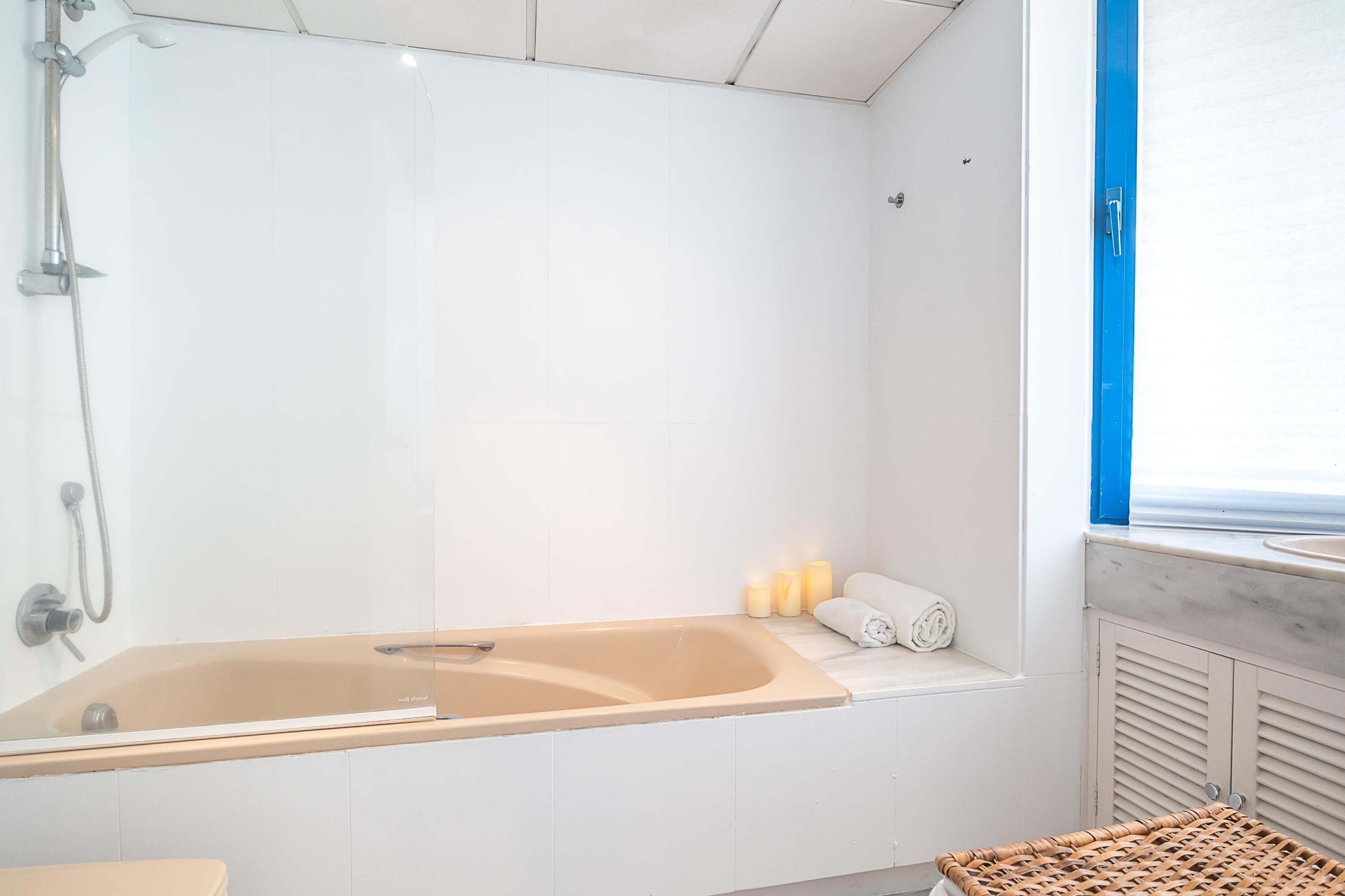 A modern bathroom with a large bathtub, a shower, and a window with a view.