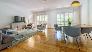 A spacious living area with a wooden floor, a dining table with chairs, a sofa, and a television on a cabinet. - Duplex Marbella Concordia Close To Beach (Marbella)