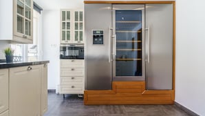 A modern kitchen with a built-in stainless steel refrigerator, white cabinetry, and a wooden accent on the lower cabinets. - Duplex Marbella Concordia Close To Beach (Marbella)