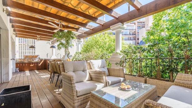 An outdoor patio with wicker furniture, a glass table, and a view of the city. - Duplex Marbella Concordia Close To Beach (Marbella)