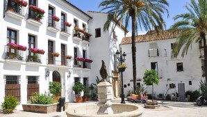 A courtyard with a fountain, potted plants, and a scooter. - Hacienda Playa Beach And Pool (Marbella)