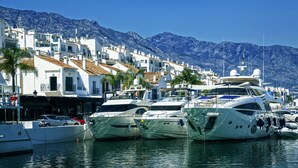 A marina with several yachts docked, white buildings with red-tiled roofs, and a mountainous backdrop. - Hacienda Playa Beach And Pool (Marbella)