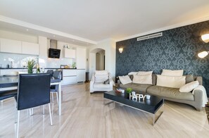 Ett modernt vardagsrum med en soffa, ett soffbord och en matplats med ett bord och stolar.