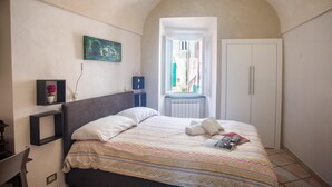 A bedroom with a bed, a window, a radiator, and a door. - Casa Felice in San Remo (Sanremo)