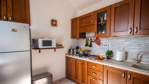 A kitchen with wooden cabinets, a microwave, a stove, and a sink. - Casa Felice in San Remo (Sanremo)