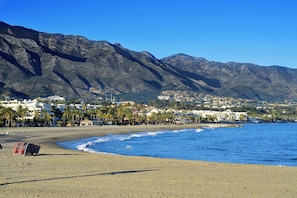 A coastal town with a beach, mountains, and residential buildings.