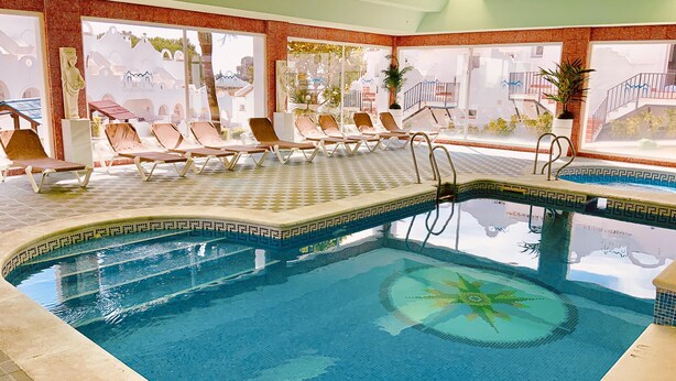 An indoor swimming pool with sun loungers and a decorative mosaic border. - Marbella Resort 7 Pool Whirlpool Sauna (Marbella)
