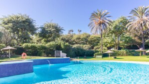 Une piscine à l’eau d’un bleu cristallin, entourée d’une végétation luxuriante et de palmiers.