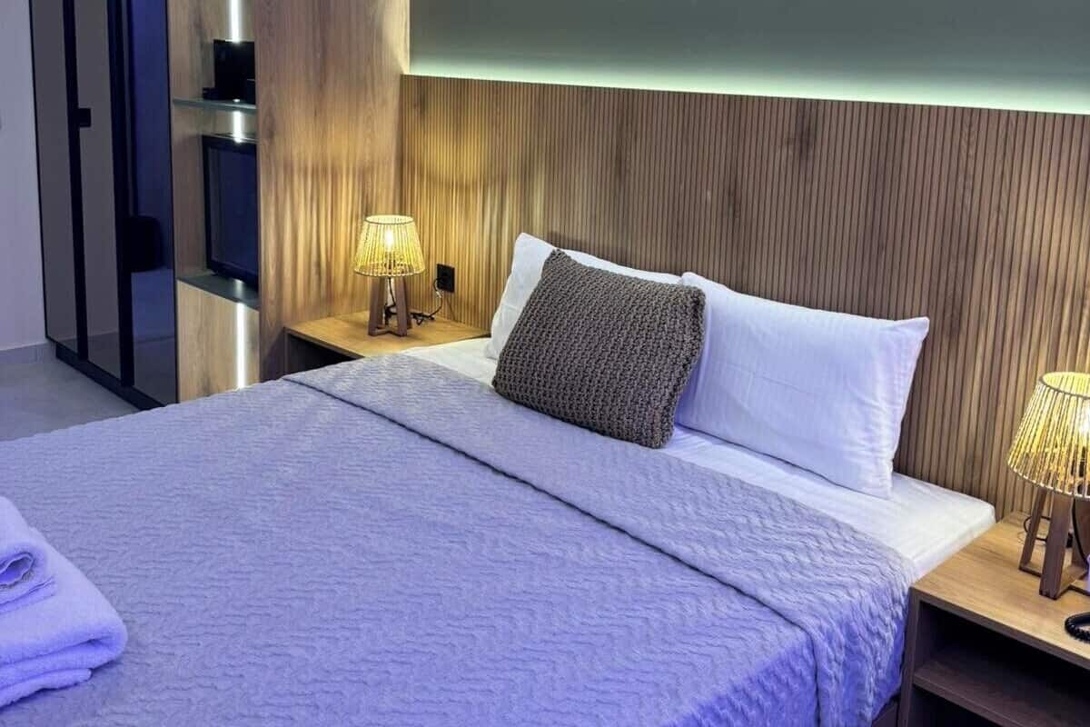 Un dormitorio moderno con una cama grande, cabecera de madera, lámparas de noche y un armario empotrado.