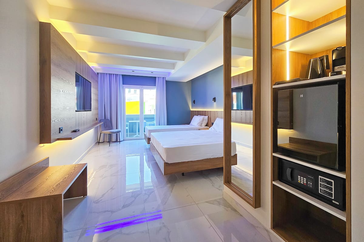 Una habitación de hotel moderna con una cama grande, televisión, minibar y balcón con vistas.