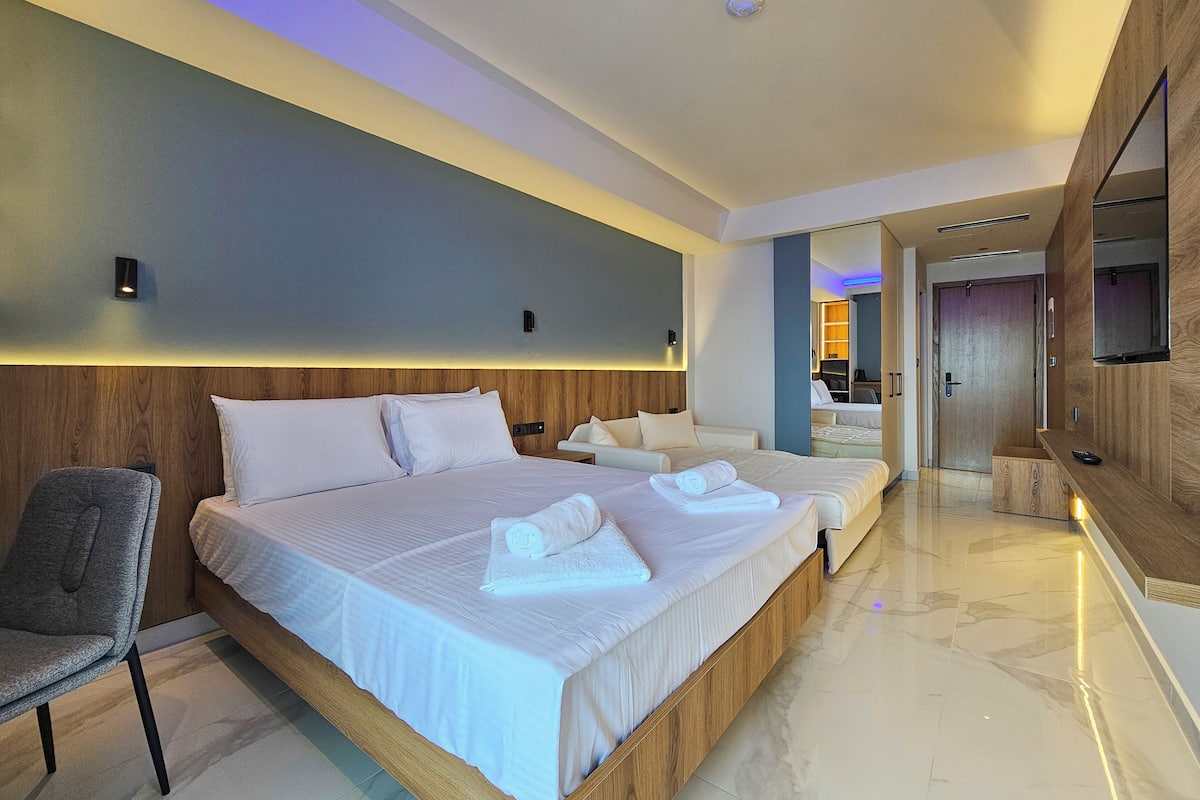 Una habitación de hotel moderna con una cama grande, un área de descanso y una pared de acento de madera.