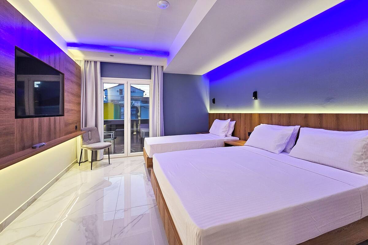Una habitación de hotel moderna con una cama grande, un televisor de pantalla plana en la pared y un balcón con vistas a la ciudad.