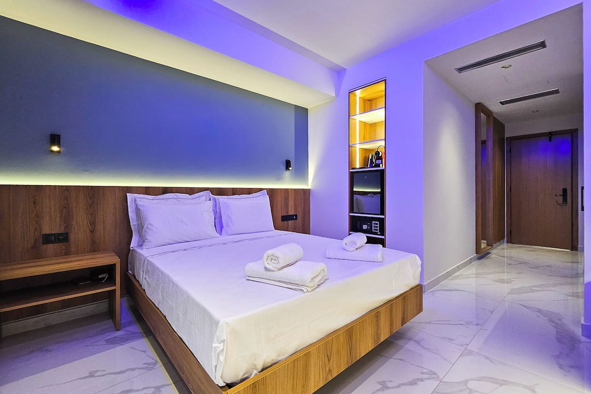 Una habitación de hotel moderna con una cama grande, estanterías integradas y un vestidor.