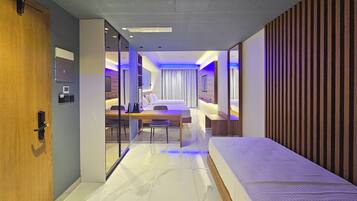 A modern hotel room with a bed, desk, and seating area.