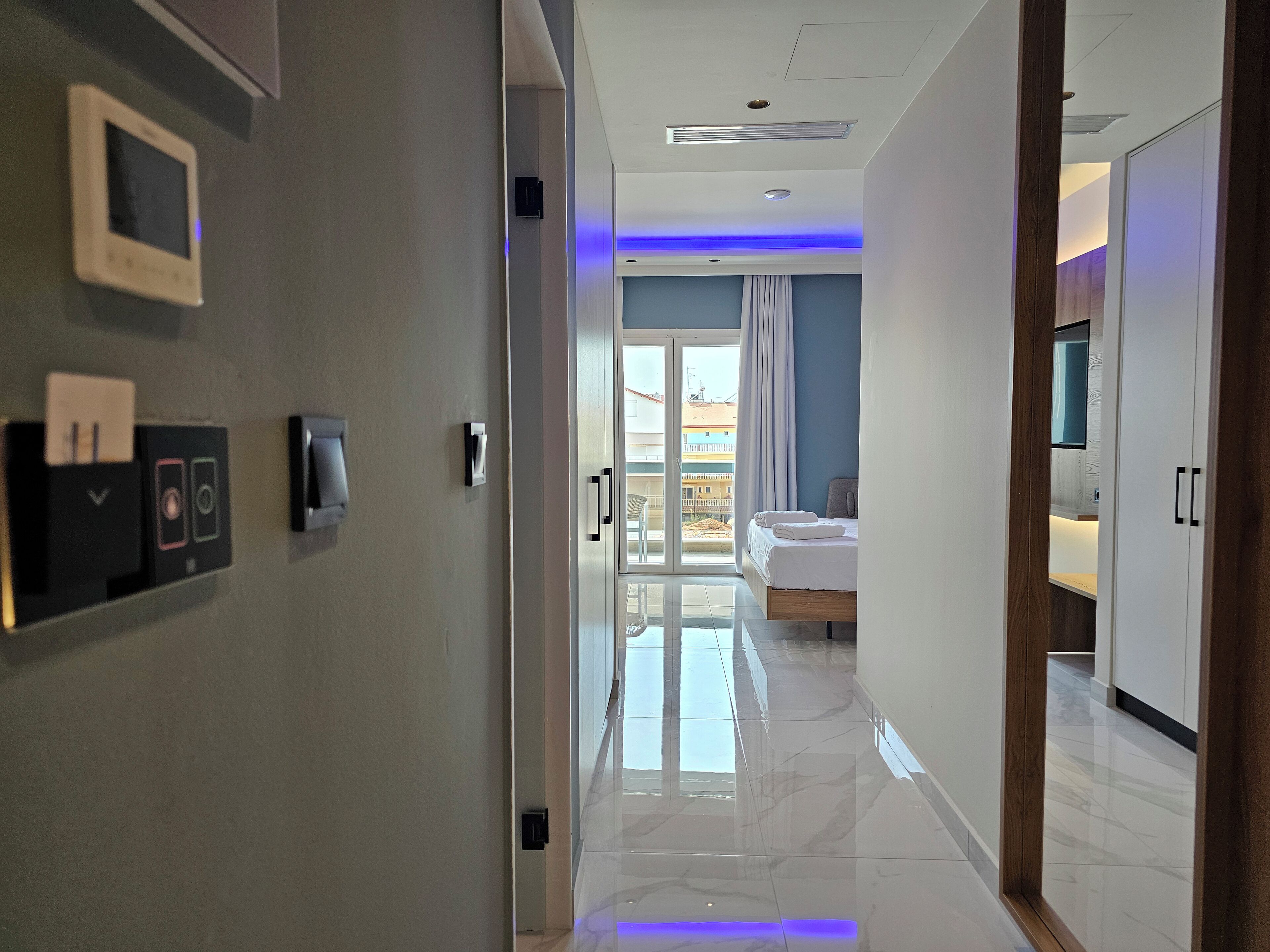 A hotel hallway with a bed, a bathroom, and a balcony.