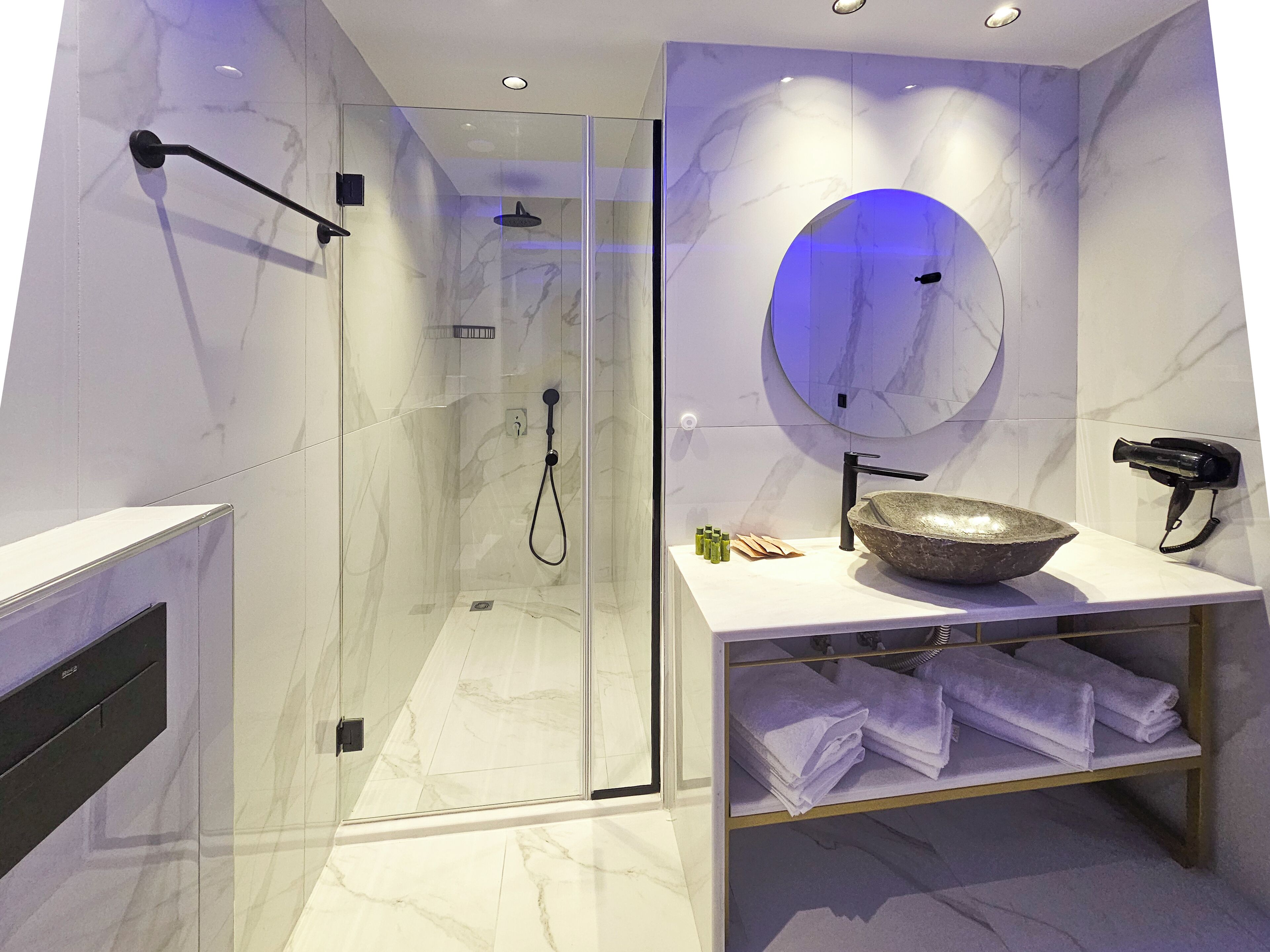 A modern bathroom with a glass-enclosed shower, a marble-tiled vanity with a large bowl sink, and a towel rack.