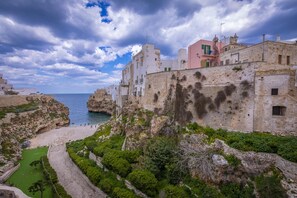A coastal town with historic stone buildings, a rocky coastline, and a clear view of the sea.