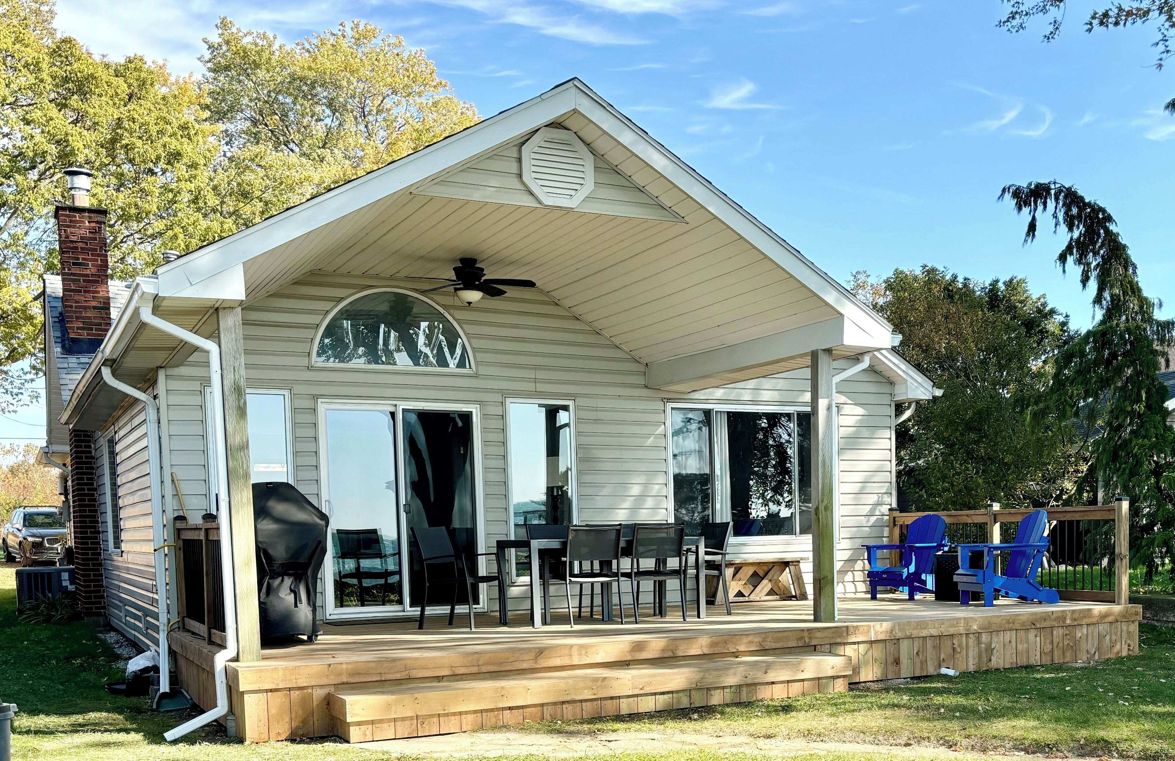 A house with a covered porch, a chimney, and a deck with outdoor furniture.