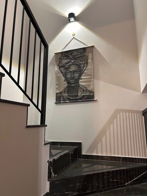 A staircase with black railings and a black marble finish, leading to a landing with a wall-mounted artwork. - Limassol Urban Beach Retreat- 500m From the Beach (Limassol)