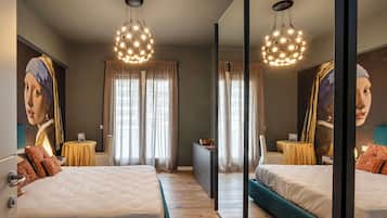 A hotel room with a large mirror, two beds, a wooden floor, and a ceiling light fixture.