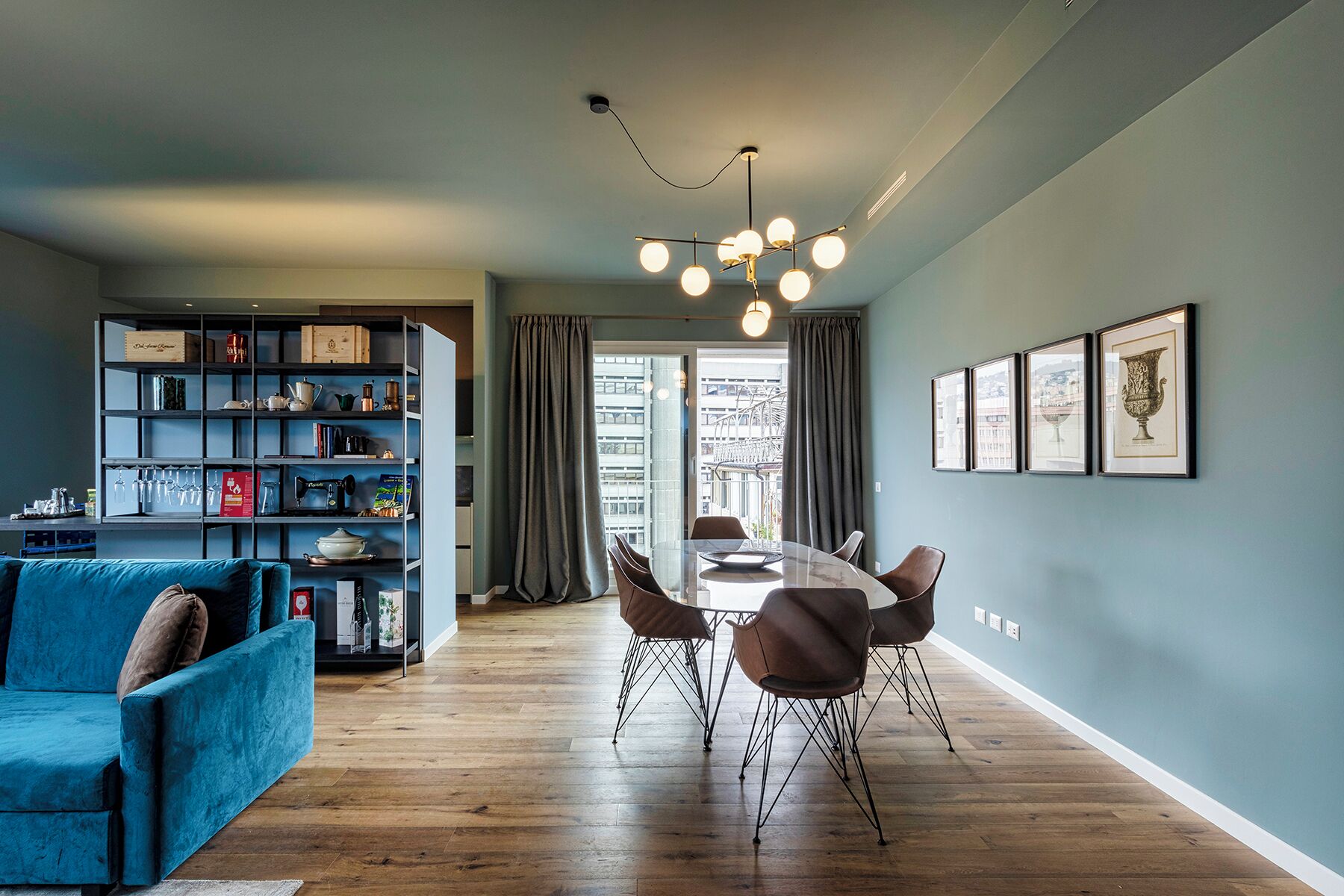 A modern living room with a dining table, blue sofa, and a bookshelf.