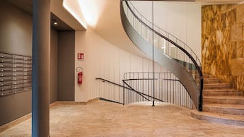 A modern interior with a spiral staircase, a fire extinguisher, and a marble wall.