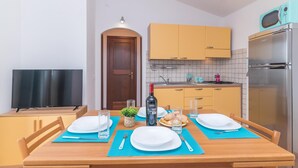A compact kitchen with a microwave, refrigerator, and a small dining area with a table set for two. - Nicole House With Stunning View And Pool (Badesi)