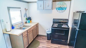 A kitchen with wooden cabinets, a stainless steel refrigerator, a stove, and a clock on the wall.