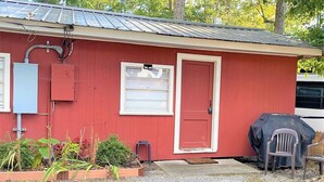 A red building with a door, a window, and a covered grill.