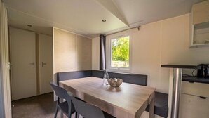 Cocina compacta con zona de comedor, que incluye una mesa de madera, sillas modernas y una ventana con vistas a zonas verdes.