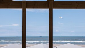 Blick auf einen Strand durch eine hölzerne Konstruktion, bewölkter Himmel.