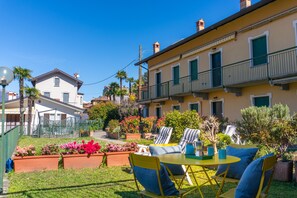 Un patio con mobiliario exterior, una mesita y plantas en macetas.