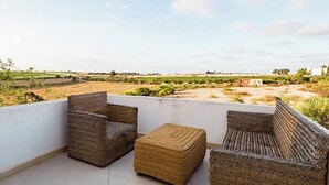 Un balcón con mobiliario de mimbre y vistas al paisaje rural.