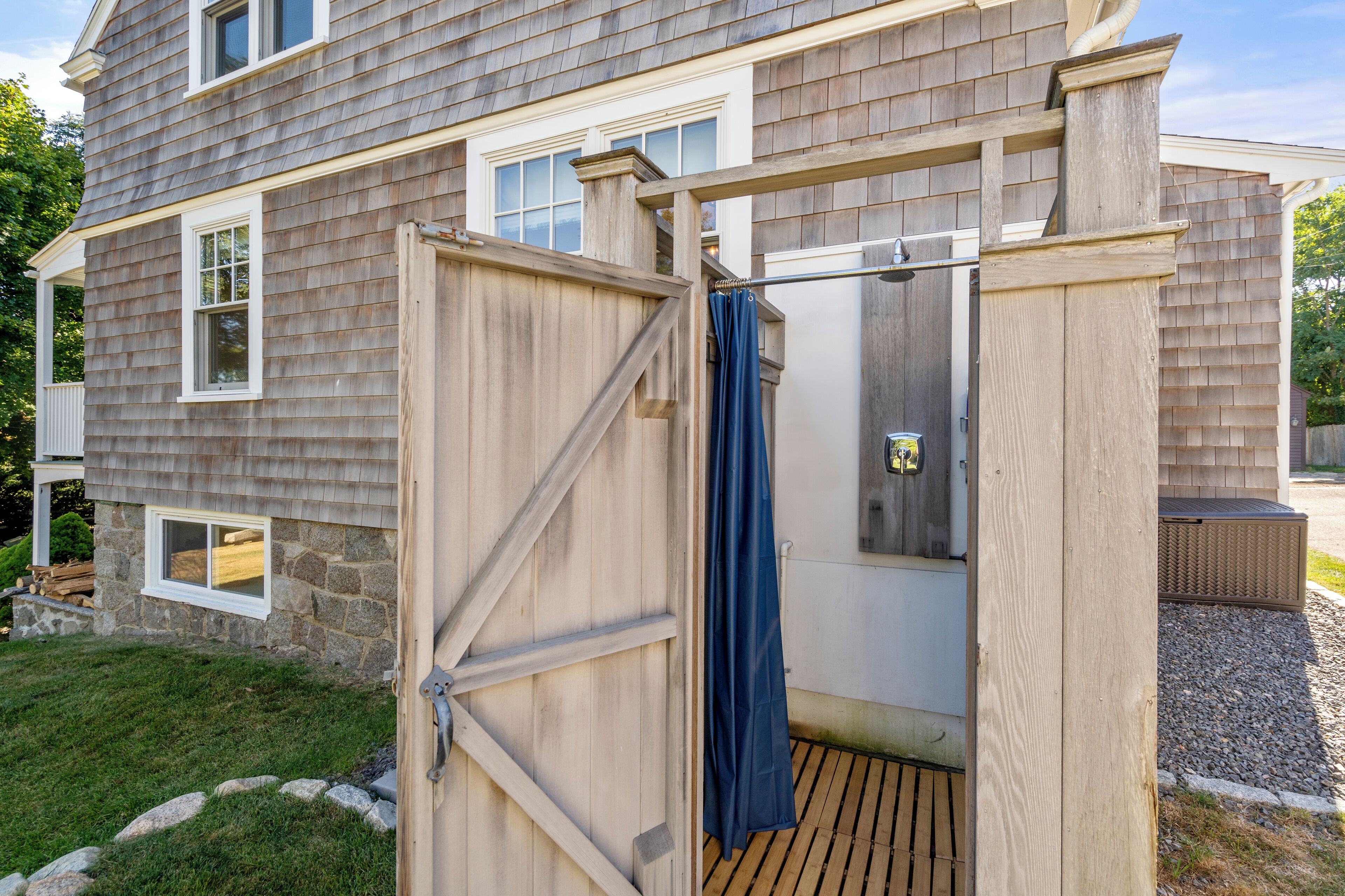 A wooden deck attached to a house with a stone foundation, a small window, and a door.