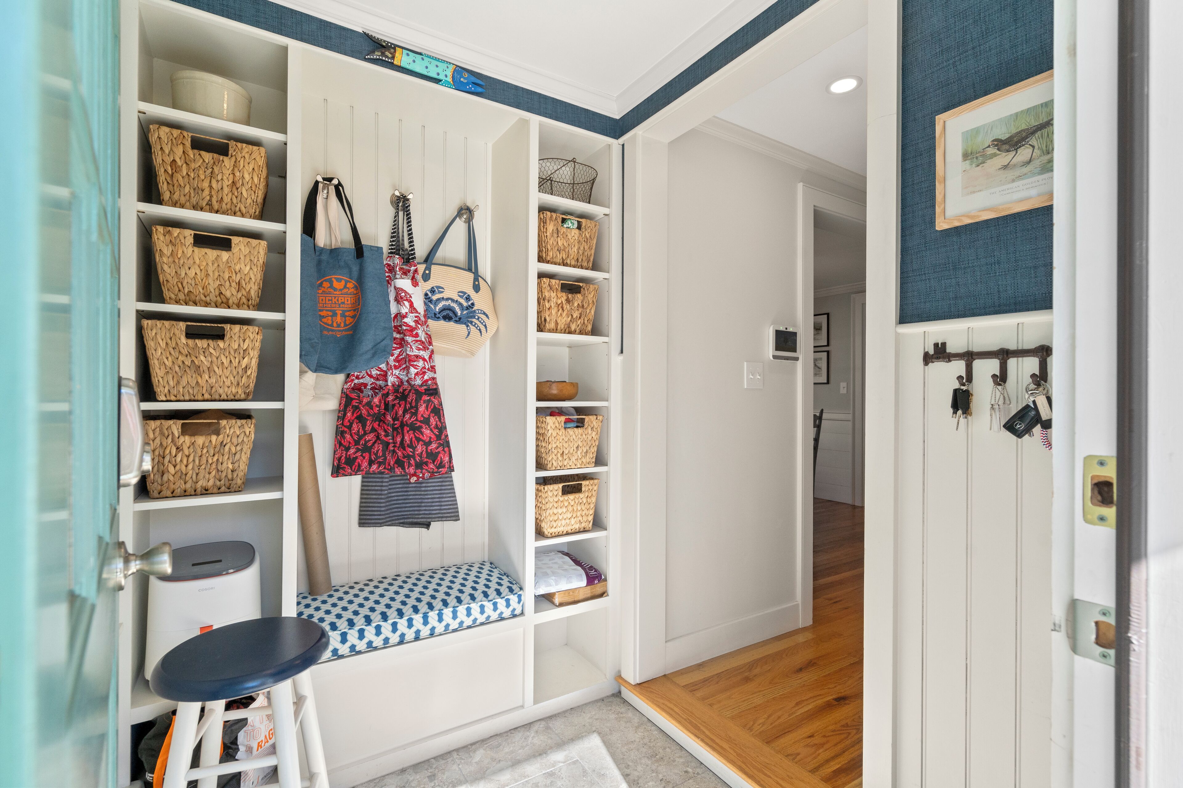 A well-organized entryway with a bench, baskets, and a coat rack.