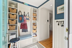 A well-organized entryway with a bench, baskets, and a coat rack.
