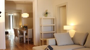 A living room with a sofa, a dining table with chairs, a bookshelf, and a lamp. - Palagio 1 in Chianti With Shared Pool (Rignano sull'Arno)